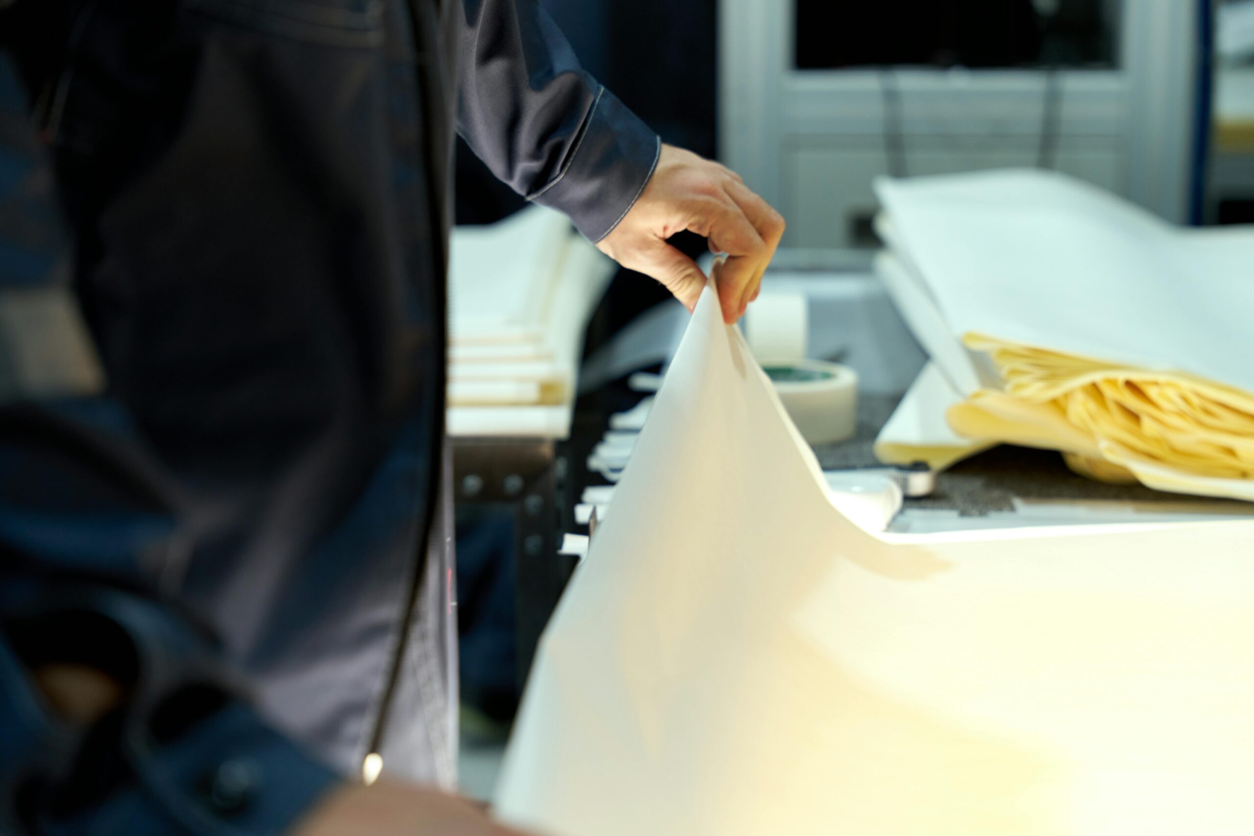 An industrial worker manages large sheets in a manufacturing setting, focusing on precision and quality.