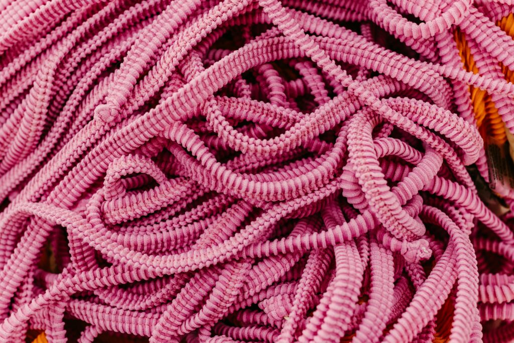 Detailed close-up of vibrant pink textured cords intertwined, capturing intricate patterns.